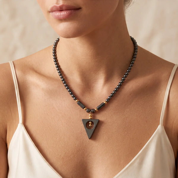 Collier pendentif triangle ajouré en hématite naturelle porté par une femme, perles dorées