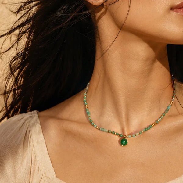 Collier perle pierre naturelle en aventurine verte porté par une femme, chaîne et perles dorées