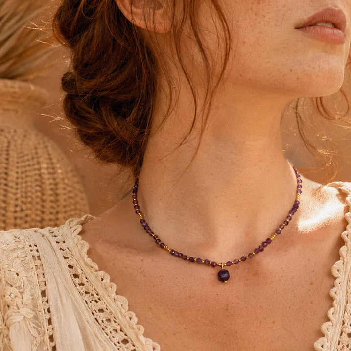 Collier perles fines en améthyste porté par une femme, chaîne et perles dorées