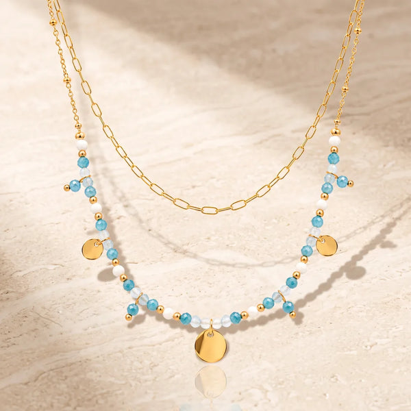 Collier pierre bleue CALYA® en apatite bleue et aigue-marine, double rang doré à médaillons et pampilles