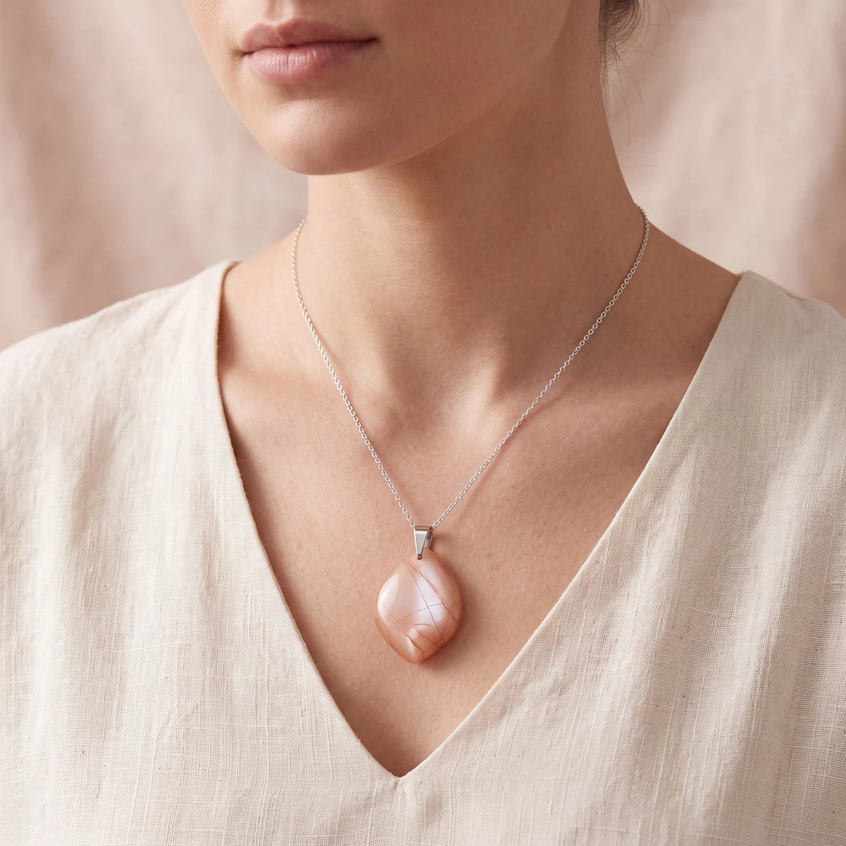 Pendentif pierre de lune pêche porté par une femme, pierre plate forme libre orange