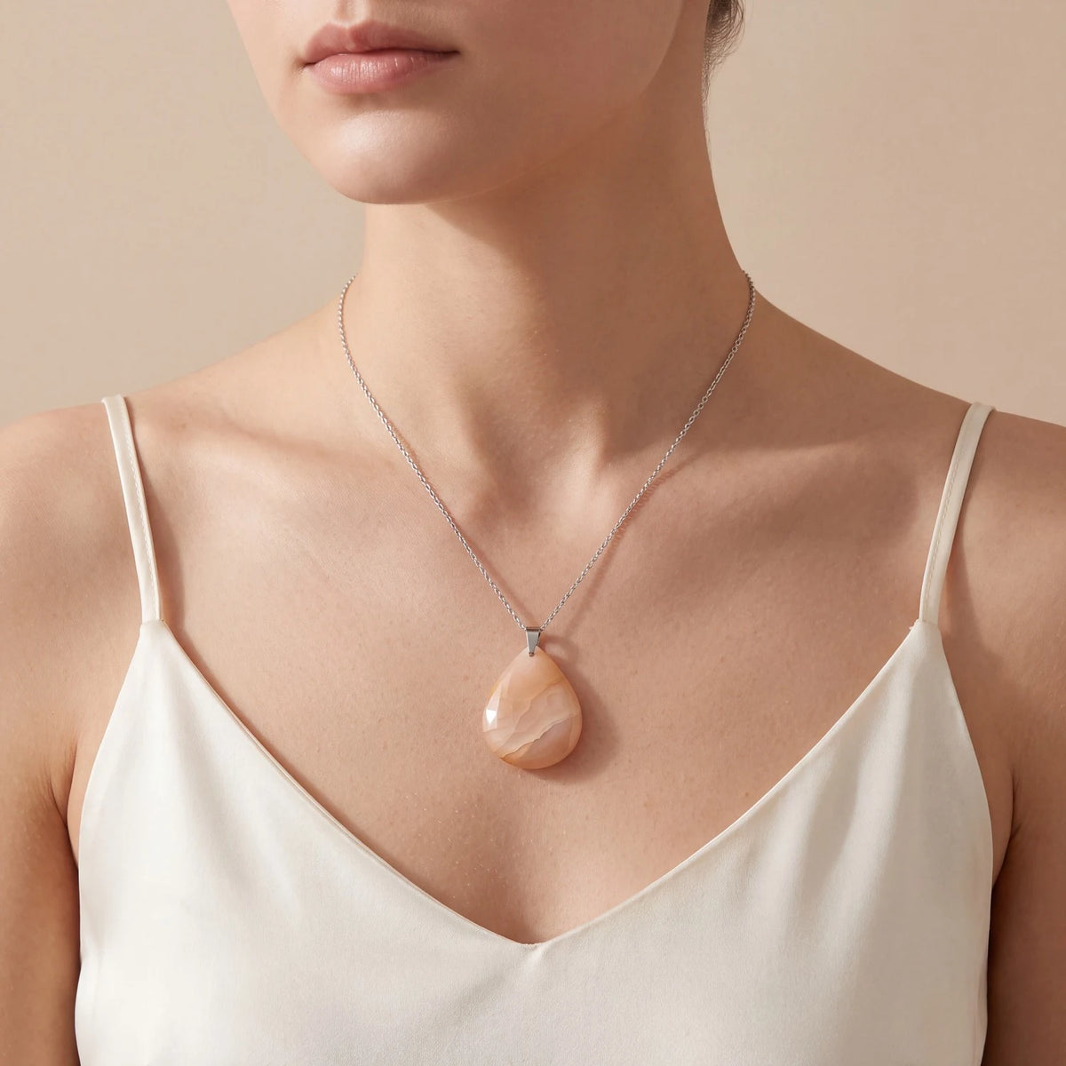 Collier pierre de lune orange porté par une femme, pendentif goutte plat couleur pêche