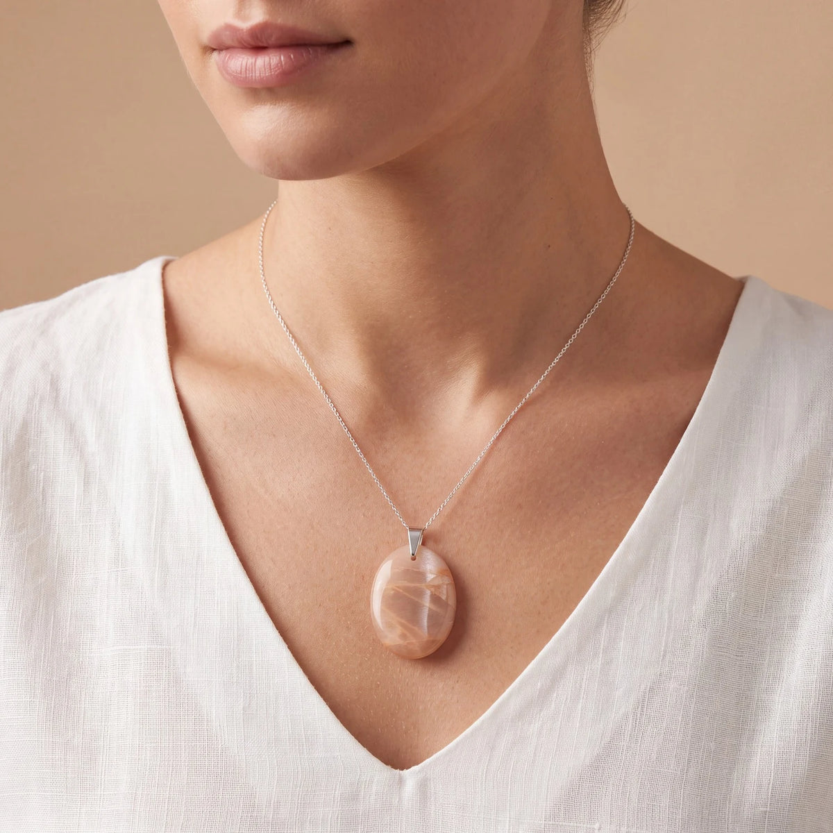 Bijou pierre de lune orange porté par une femme, pendentif ovale plat couleur abricot