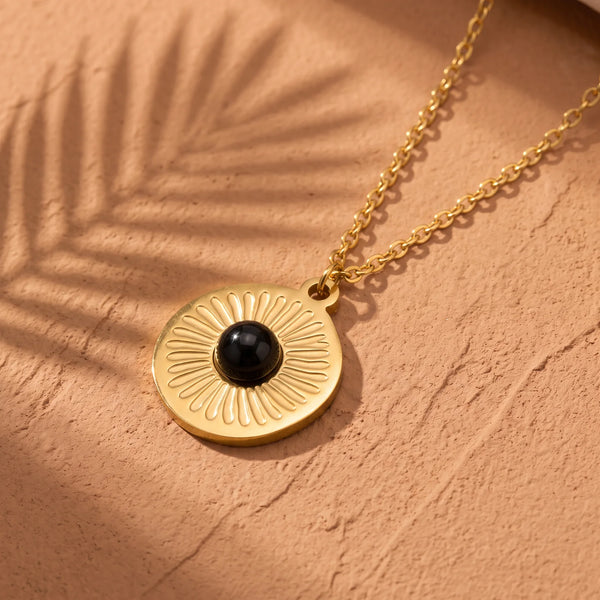 Collier pierre noire SOLAYA® : médaille soleil gravée dorée, cabochon d'onyx noir