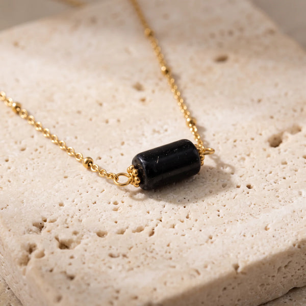 Collier pierre noire LUMIA® : tube en tourmaline noire entre deux coupelles dorées, sur chaîne fine perlée