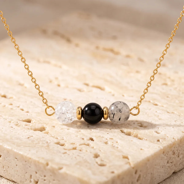 Collier pierre transparente TRINA® en cristal de roche, quartz à tourmaline et onyx, trois perles sur chaîne dorée