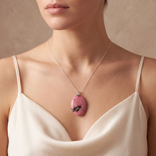 Pendentif rhodonite naturelle porté par une femme, ovale plat rose veiné de noir