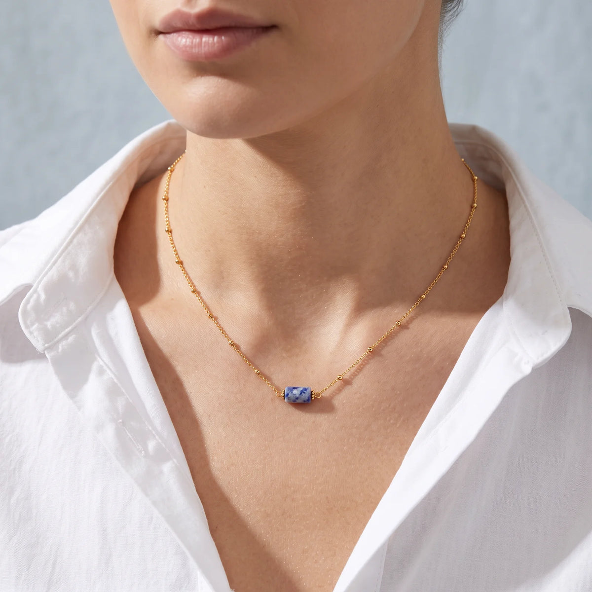Collier sodalite LUMIA® porté par une femme, tube en sodalite sur chaîne dorée