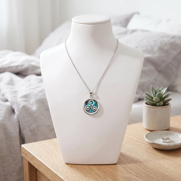 Collier triskel bleu en nacre naturelle porté sur un buste, pendentif triskel sur chaîne argentée