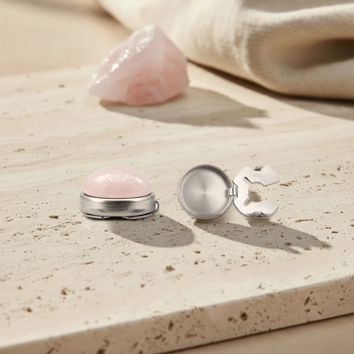 Couvre bouton de chemise en quartz rose, montré fermé et ouvert sur son clip en acier inoxydable, sur travertin
