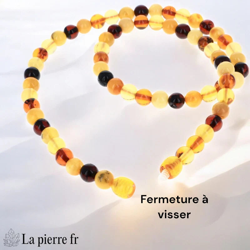 Gros plan sur les perles rondes polies d'un collier en Ambre véritable, révélant les différentes couleurs (cognac, miel, citron).