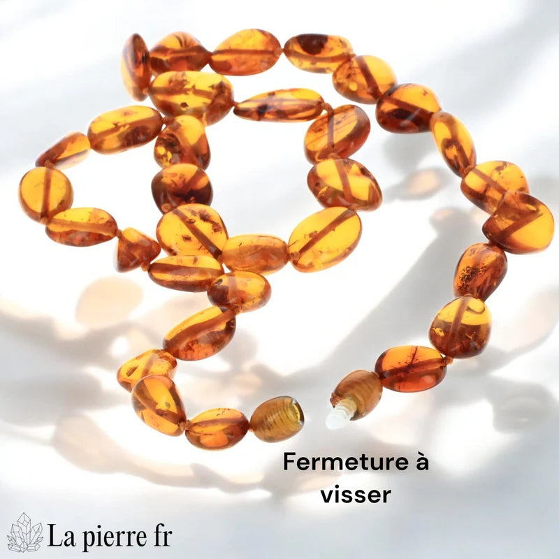 Gros plan sur les plaquettes d'un collier en Ambre véritable, révélant les inclusions et la couleur profonde du cognac.
