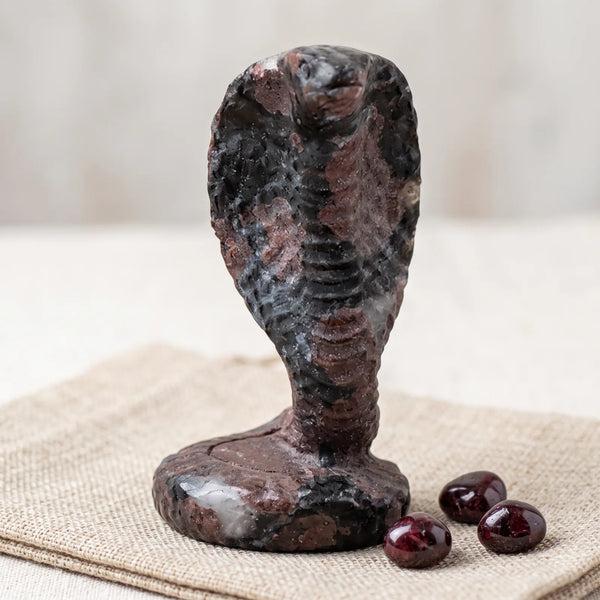 Figurine cobra en pierre naturelle sur un lin avec trois pierres roulées de grenat rouge