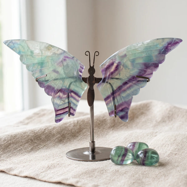 Figurine papillon en fluorine sur un lin naturel avec trois pierres roulées