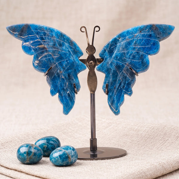 Figurine papillon en pierre naturelle apatite bleue sur un lin naturel avec trois pierres roulées