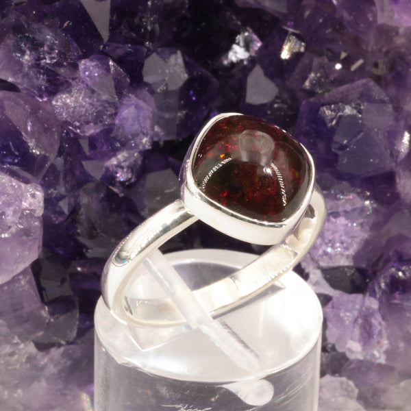 Bague opale noire portée au doigt, pièce unique en argent