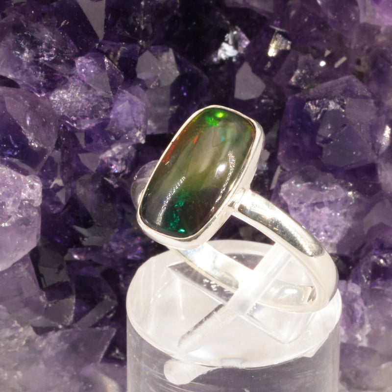 Bague opale noire portée au doigt, pièce unique en argent