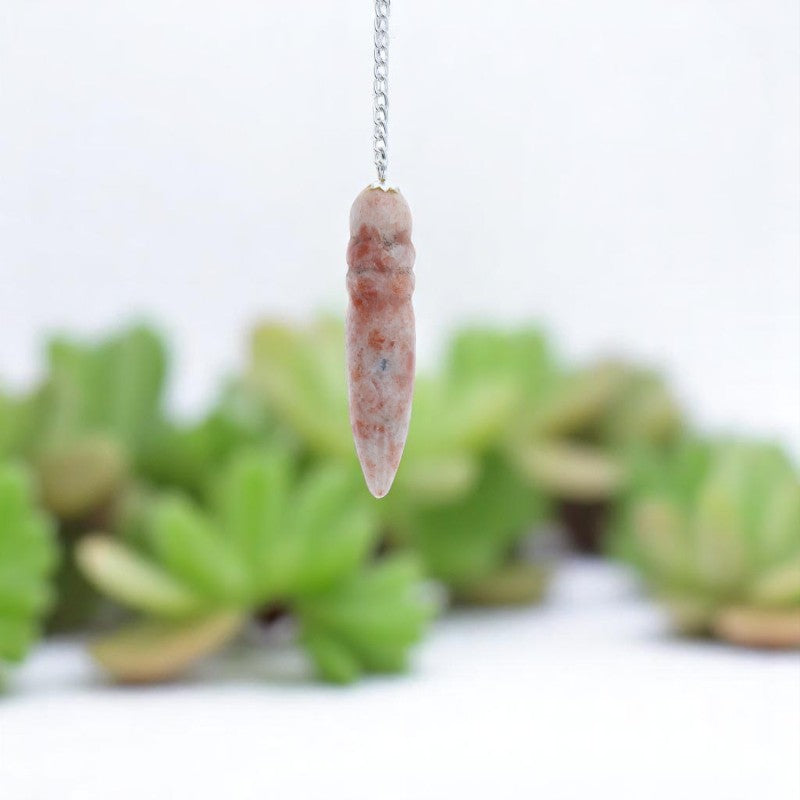 Gros plan sur la forme Thot du Pendule Égyptien (Pierre de Soleil) aux reflets orangés