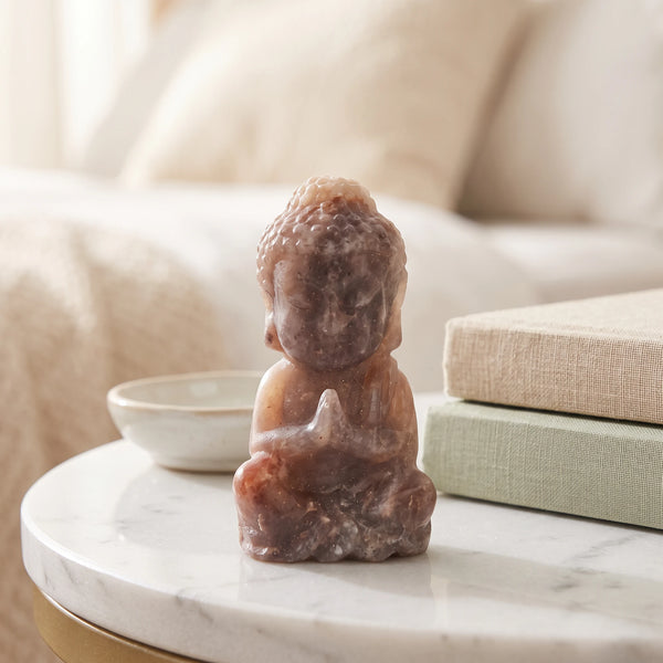 Mini Bouddha mauve en pierre de soleil et pierre de lune sur une table de chevet