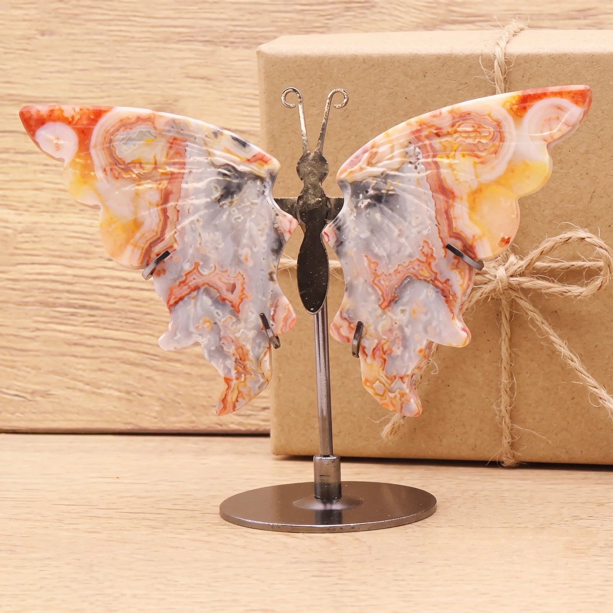 Objet papillon décoration en agate devant une boîte cadeau kraft