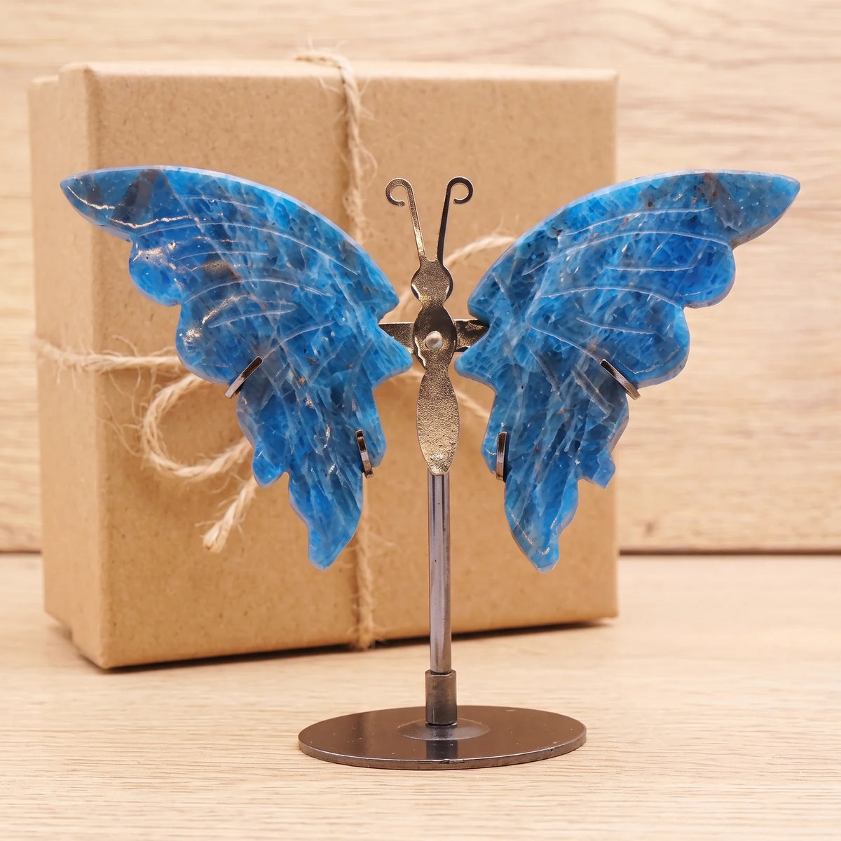 Objet papillon décoration en apatite devant une boîte cadeau kraft