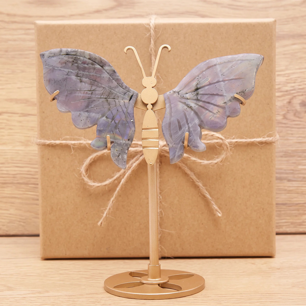 Objet papillon doré en labradorite devant une boîte cadeau kraft