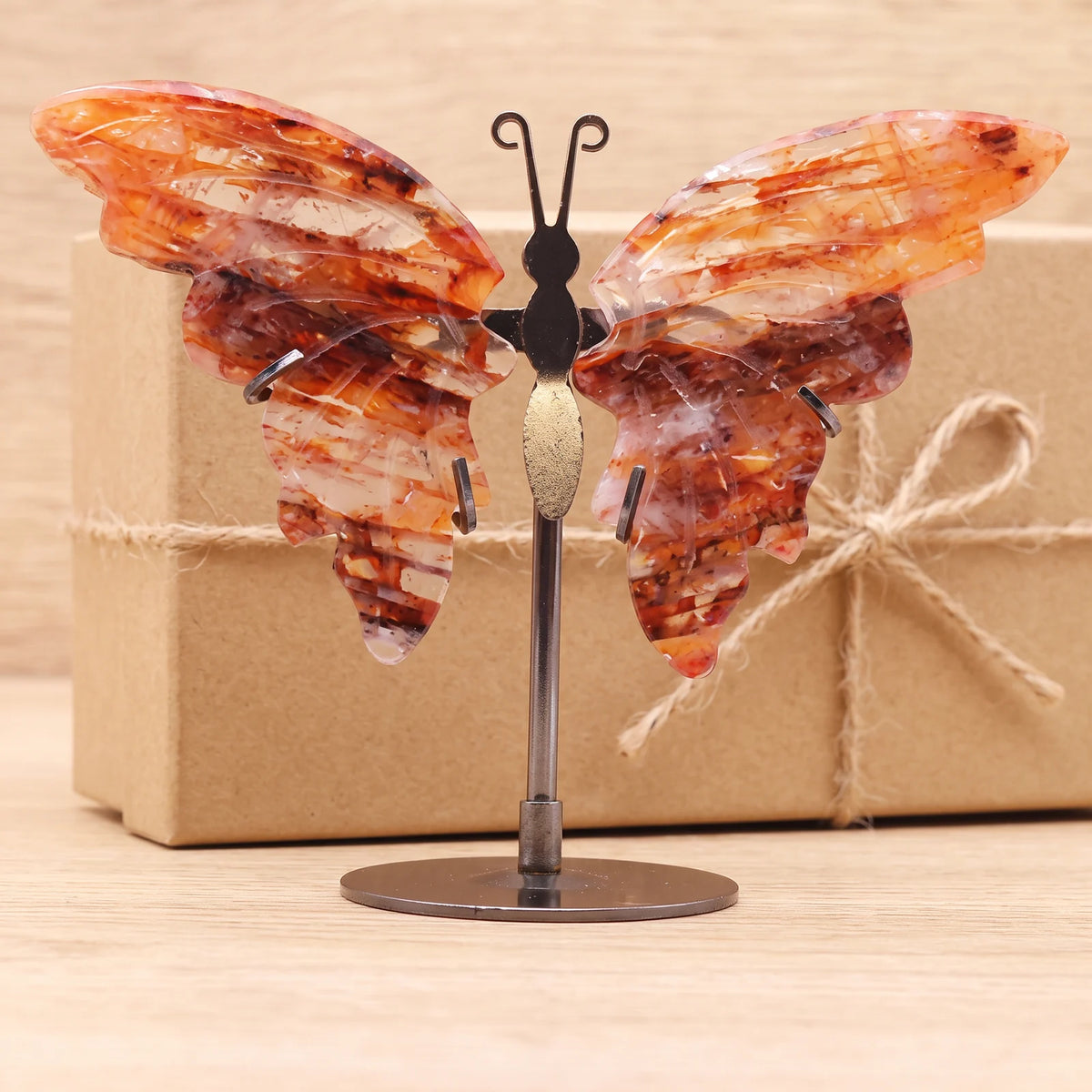 Objet papillon en pierre devant une boîte cadeau kraft, idée cadeau en quartz rouge