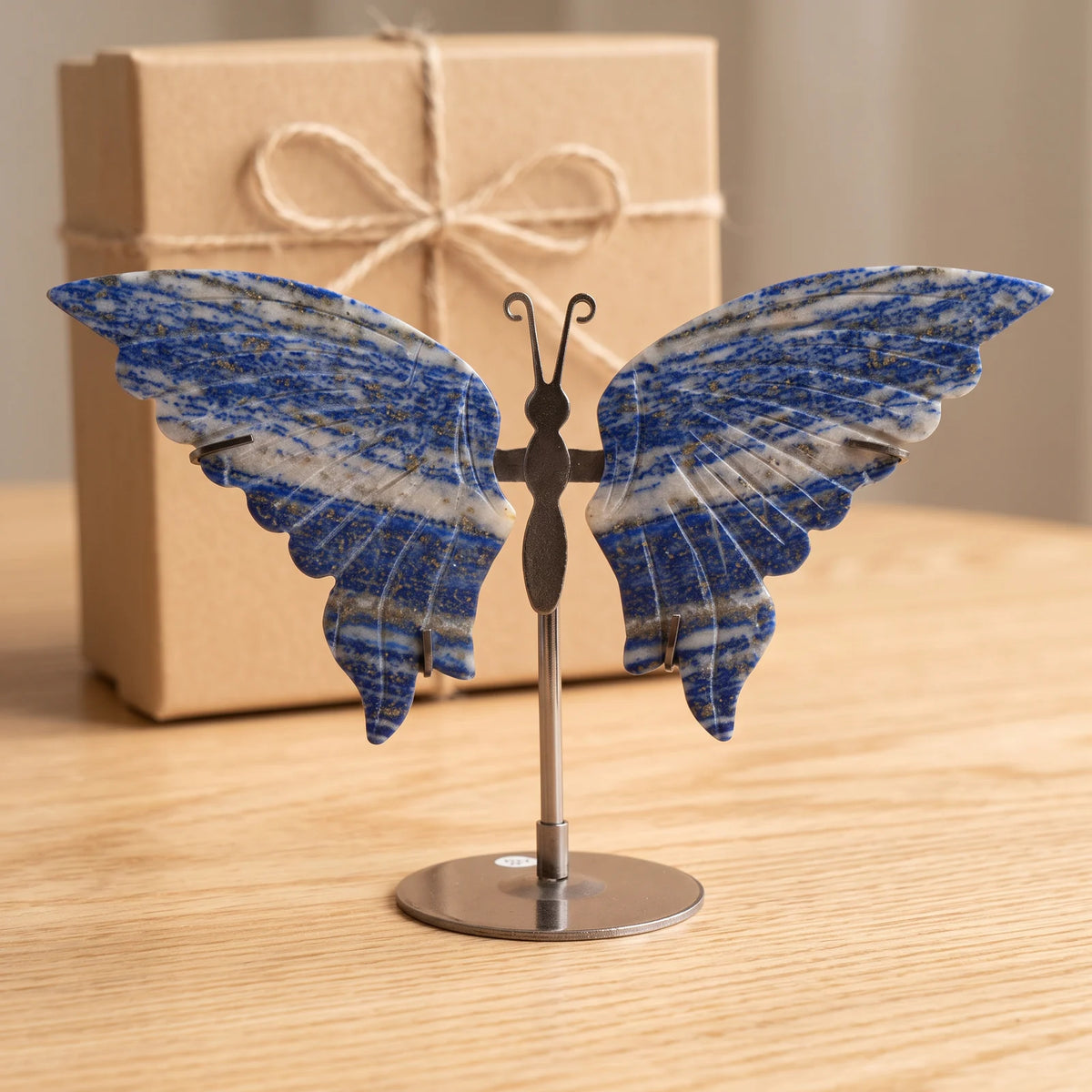 Objet papillon en lapis lazuli devant une boîte cadeau kraft