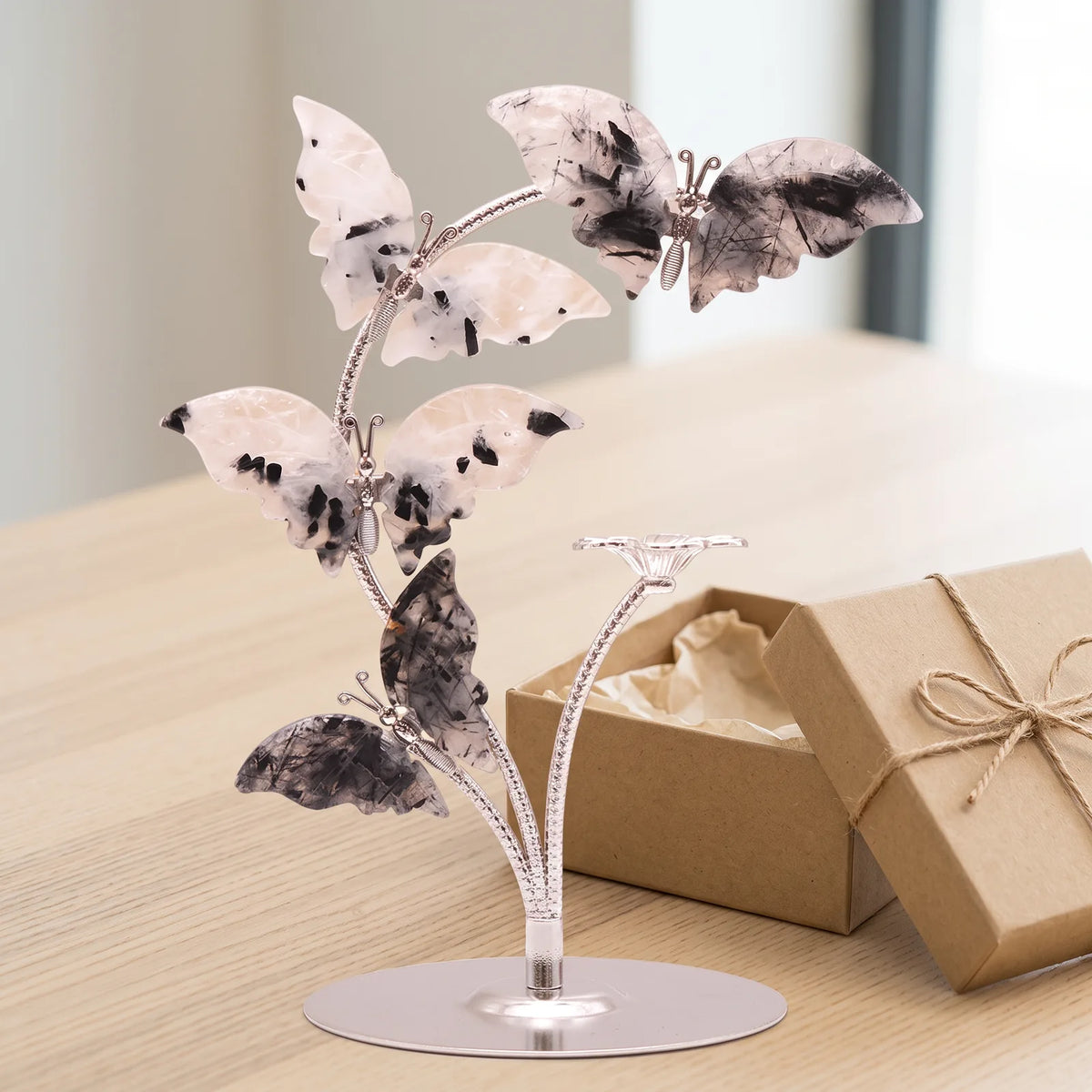 Papillon décoration en pierre devant une boîte cadeau kraft