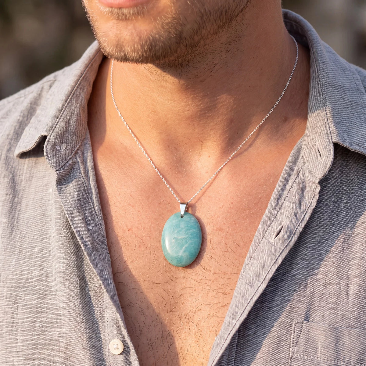 Collier amazonite homme, pendentif ovale plat bleu-vert porté sur une chemise en lin ouverte