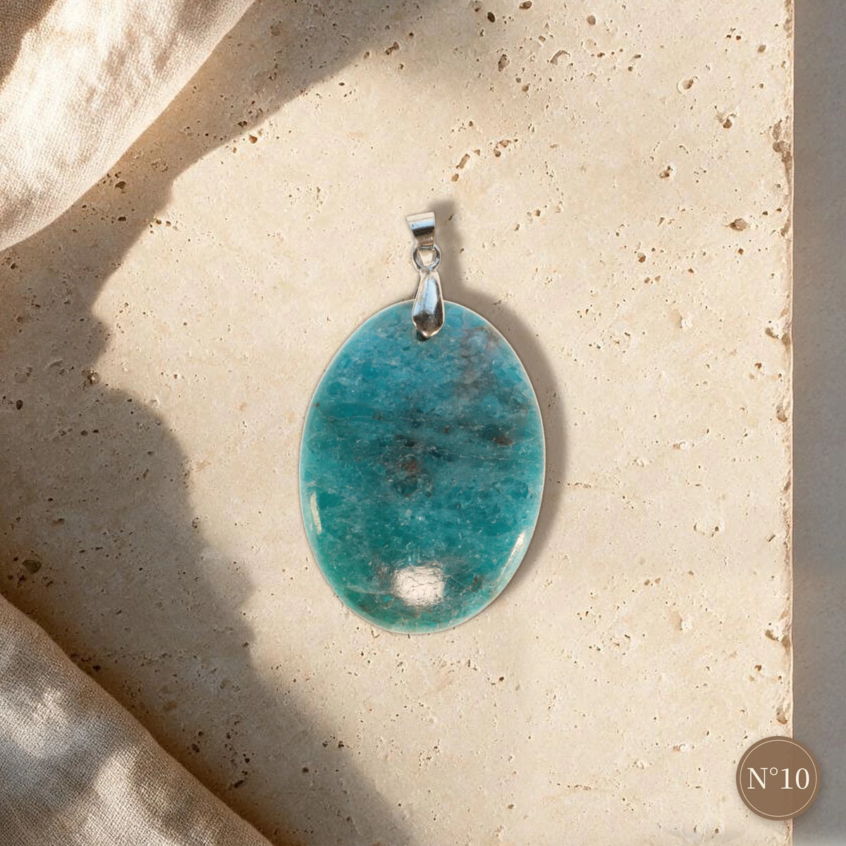 Pendentif apatite bleue pièce unique N°10, ovale bleu turquoise clair et bélière argentée sur dalle de travertin