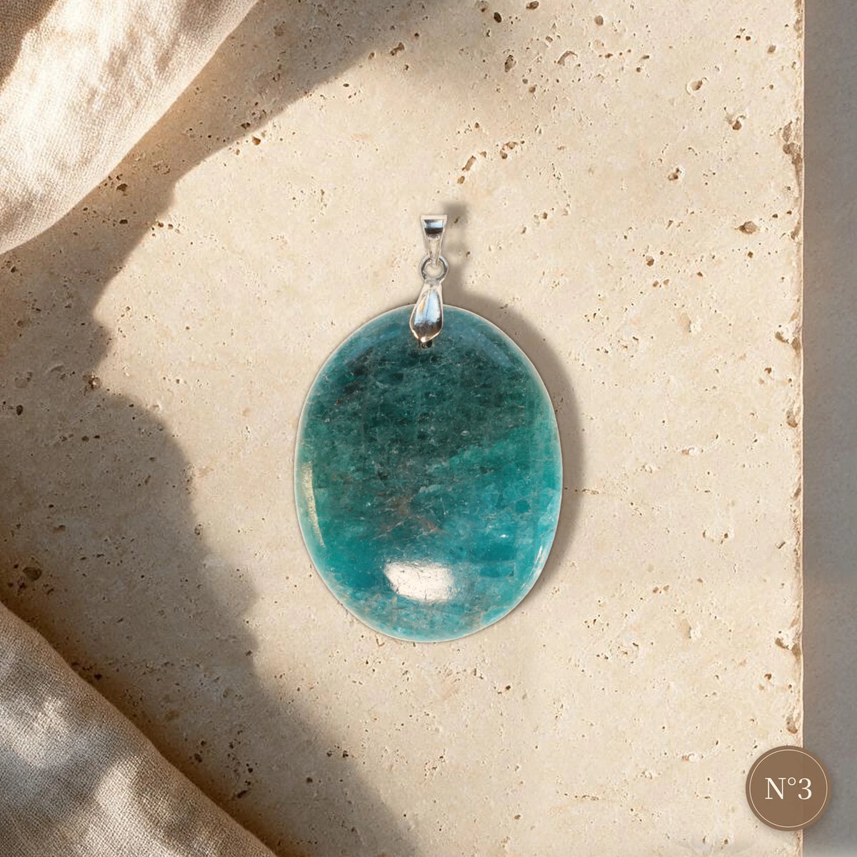 Pendentif apatite bleue pièce unique N°3, grand ovale bleu canard dégradé et bélière argentée sur travertin