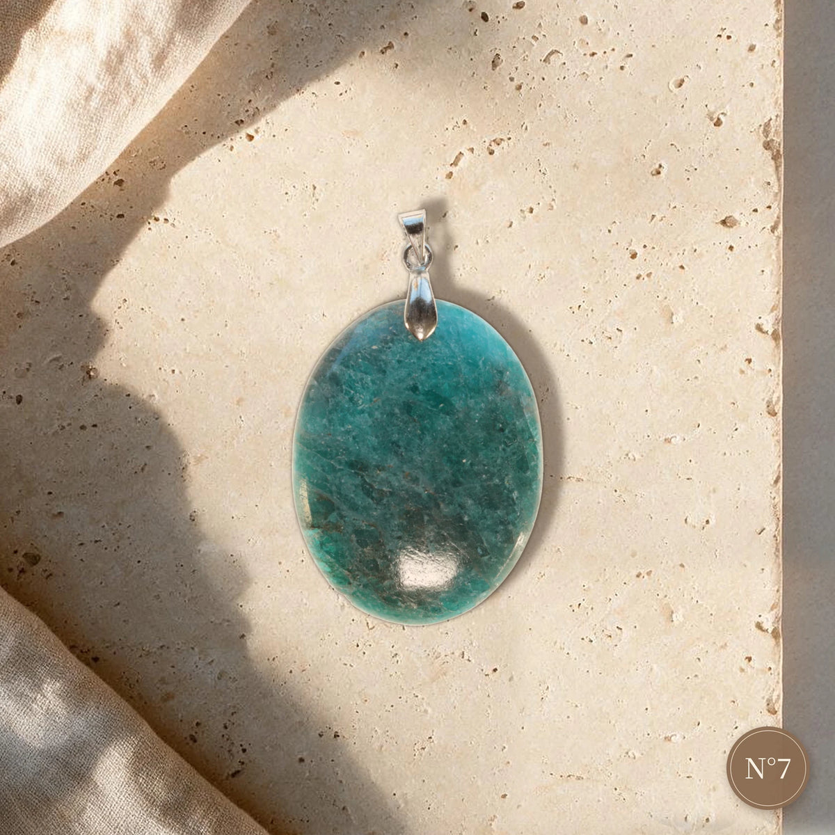 Pendentif apatite bleue pièce unique N°7, cabochon ovale bleu vert et bélière argentée posé sur travertin