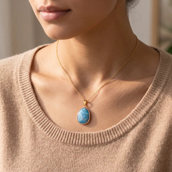 Pendentif apatite porté par une femme, collier pierre bleue sur chaîne dorée