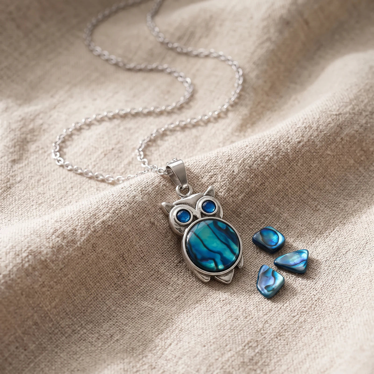Pendentif chouette en nacre d'ormeau bleue sur un lin naturel avec des éclats de nacre