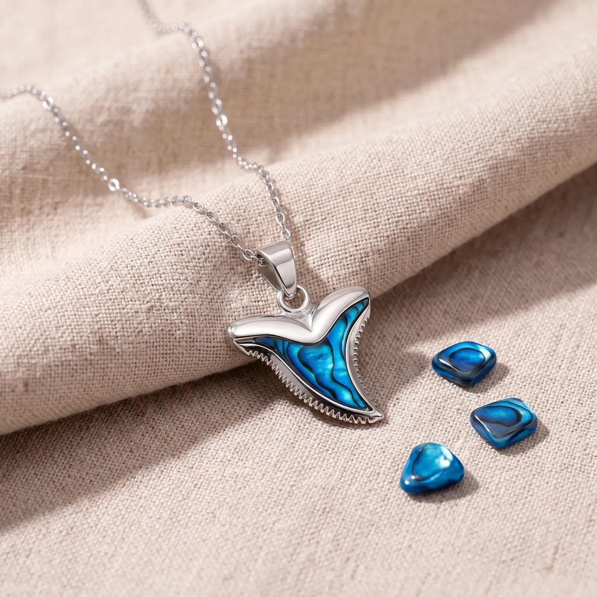 Pendentif dent de requin en nacre d'ormeau bleue sur un lin naturel avec des éclats de nacre