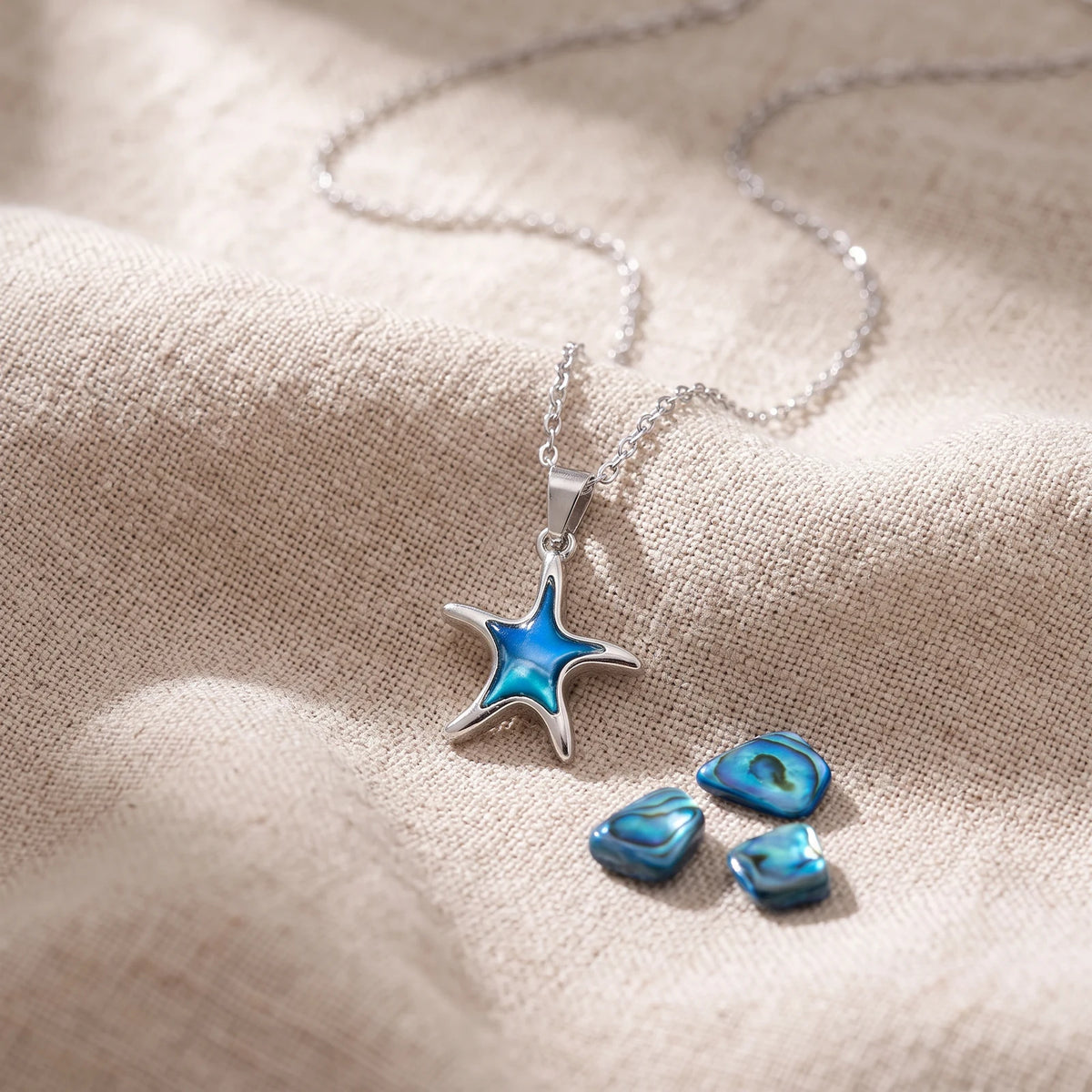Pendentif étoile de mer en nacre d'ormeau bleue sur un lin naturel avec des éclats de nacre