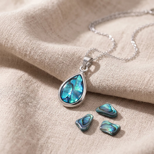 Pendentif goutte en nacre d'ormeau bleue sur un lin naturel avec des éclats de nacre