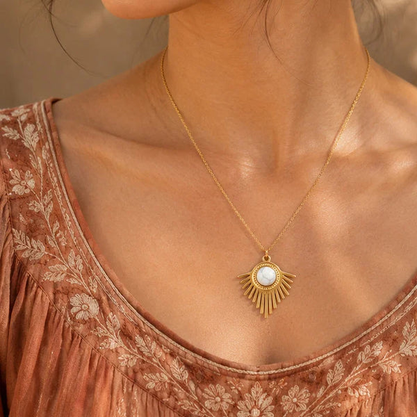 Pendentif howlite SOLENA® porté par une femme, soleil doré sur chaîne fine