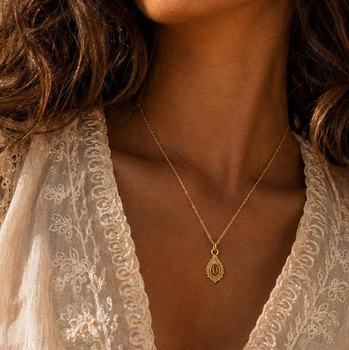 Pendentif œil de tigre ORIANE® porté par une femme, médaillon doré sur chaîne fine