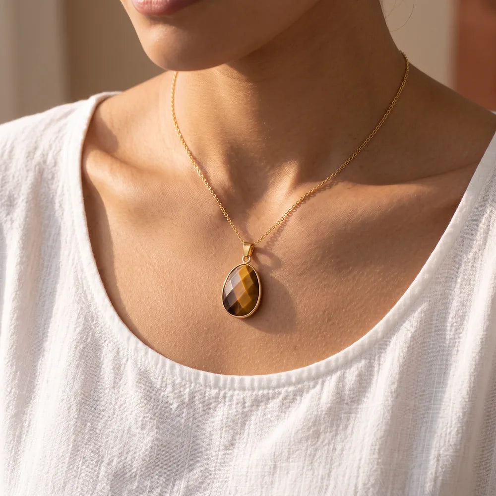 Pendentif œil de tigre porté par une femme, collier pierre marron sur chaîne dorée