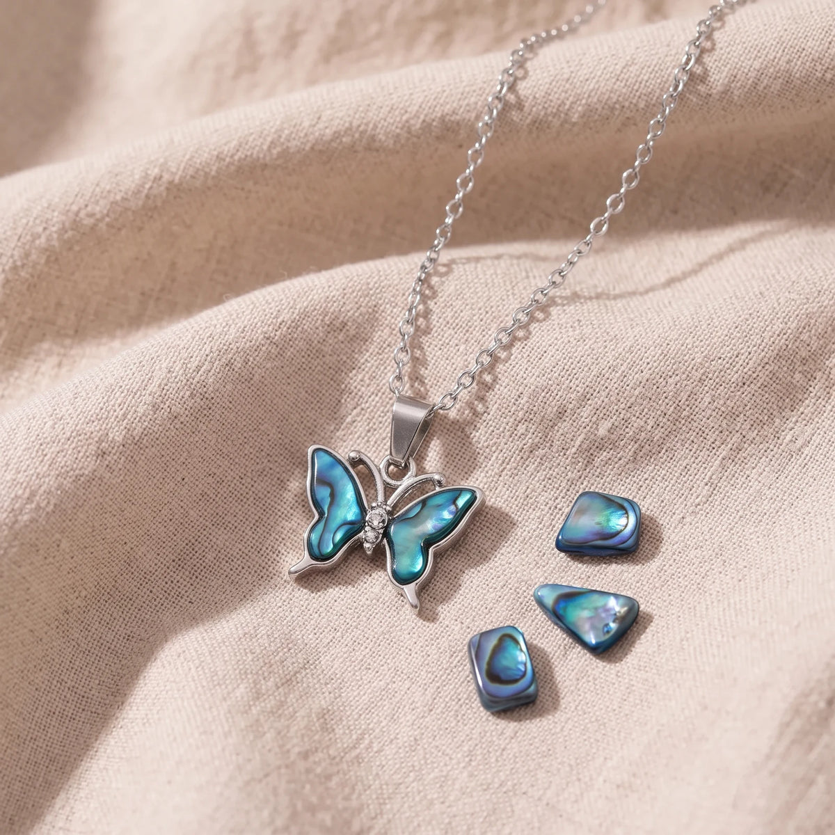 Pendentif papillon en nacre d'ormeau bleue sur un lin naturel avec des éclats de nacre