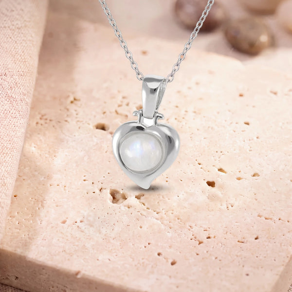 Collier pierre de lune argent, modèle en cœur d'argent, sur sa chaîne, posé sur une dalle de travertin