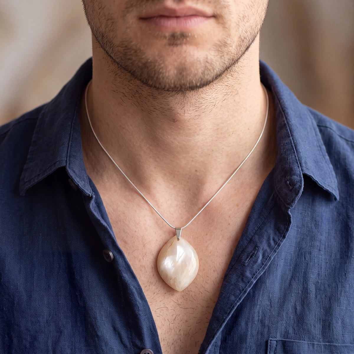 Pendentif pierre de lune beige forme libre porté par un homme sur chaîne fine