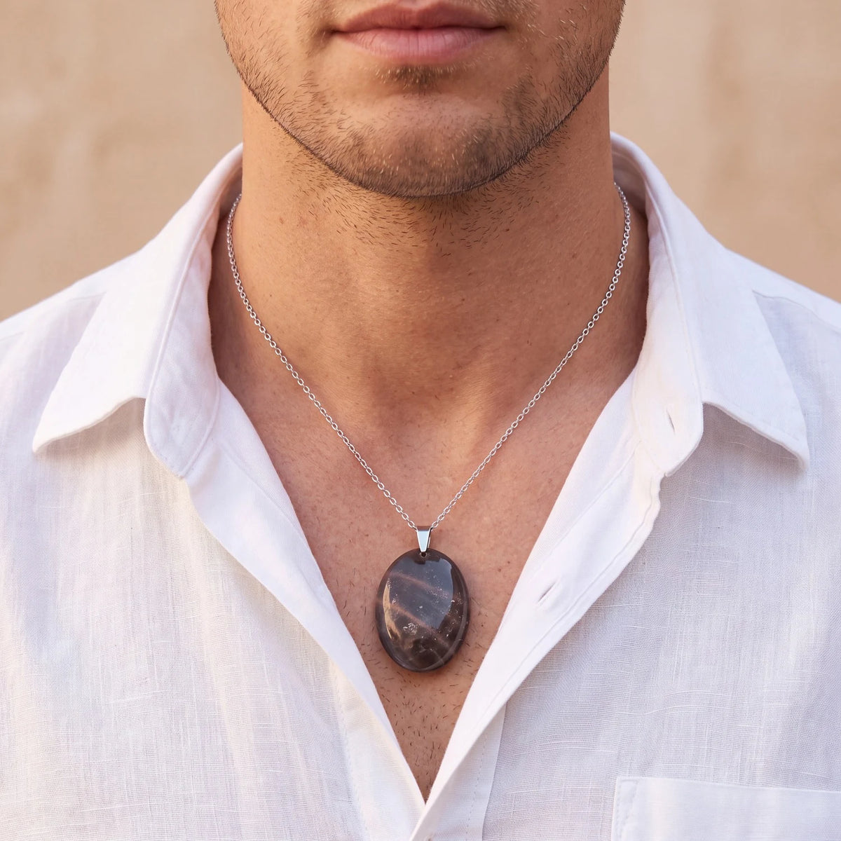 Pendentif pierre de lune noire homme, ovale plat porté sur un t-shirt avec une chemise ouverte