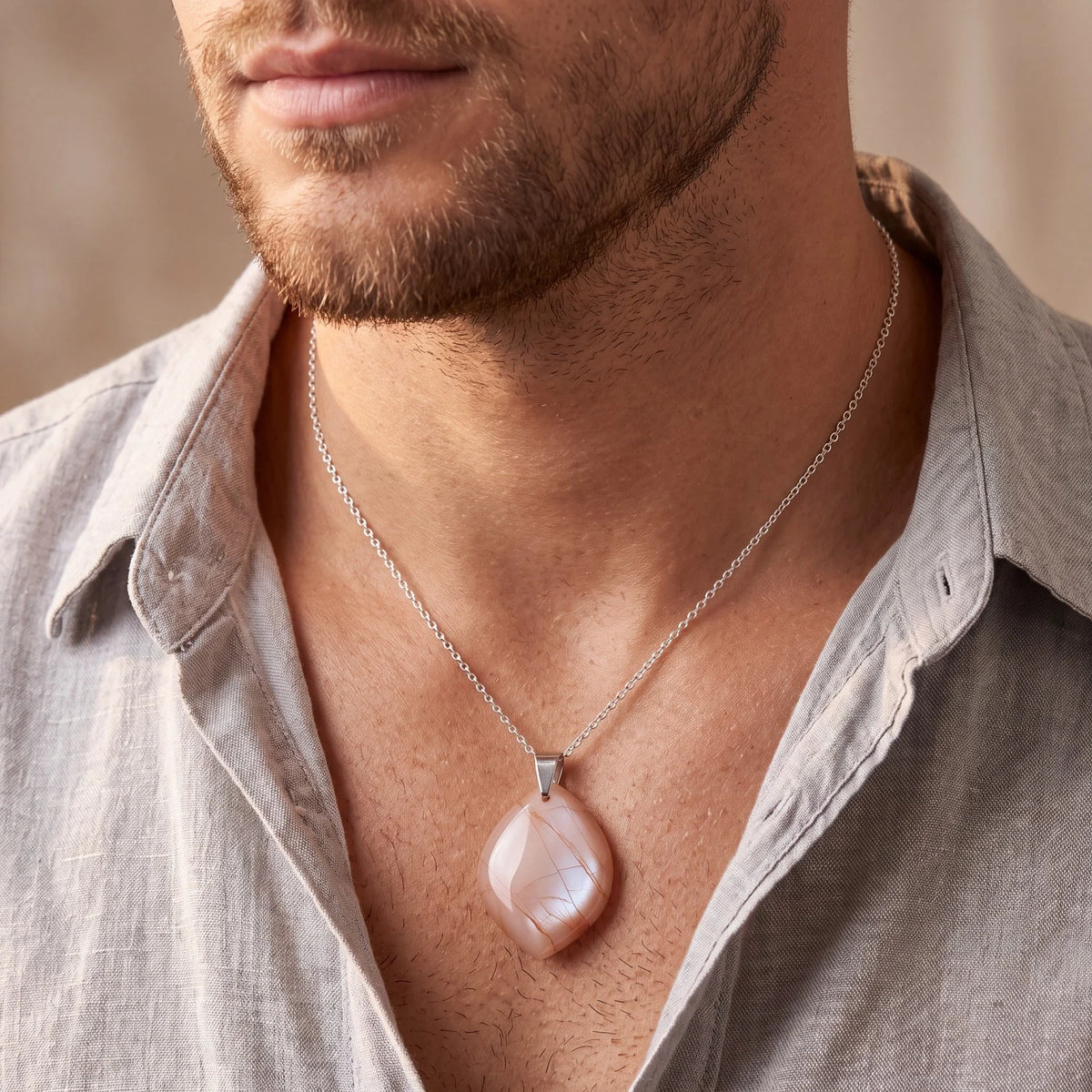 Pendentif pierre de lune orange forme libre porté par un homme sur chaîne fine