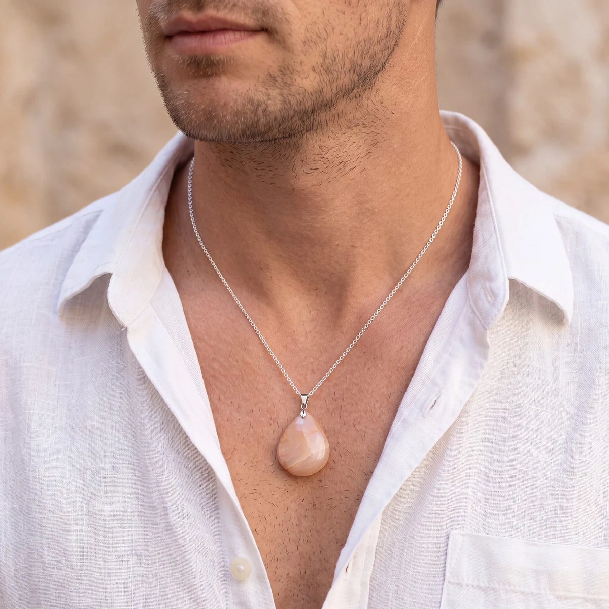 Pendentif goutte en pierre de lune orange porté par un homme, pierre plate sur chaîne