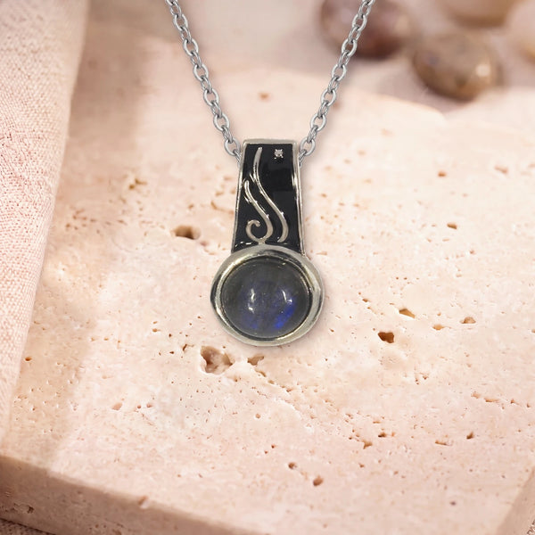 Collier labradorite lumineuse, modèle rond à bélière émaillée, sur sa chaîne, posé sur une dalle de travertin