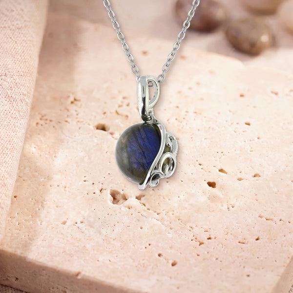 Collier labradorite homme, modèle grand rond à volutes d'argent, sur sa chaîne, posé sur une dalle de travertin
