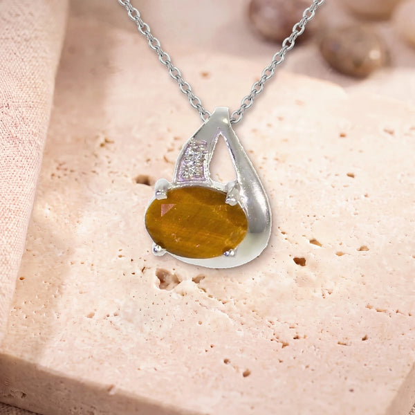 Pendentif œil de tigre facetté, modèle ovale facetté sur griffes, sur sa chaîne, posé sur une dalle de travertin